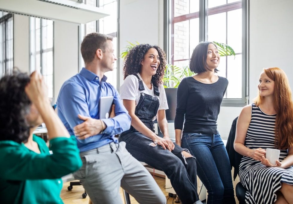 Cheerful multi-ethnic business colleagues in meeting. Male and female professionals laughing during a meeting.